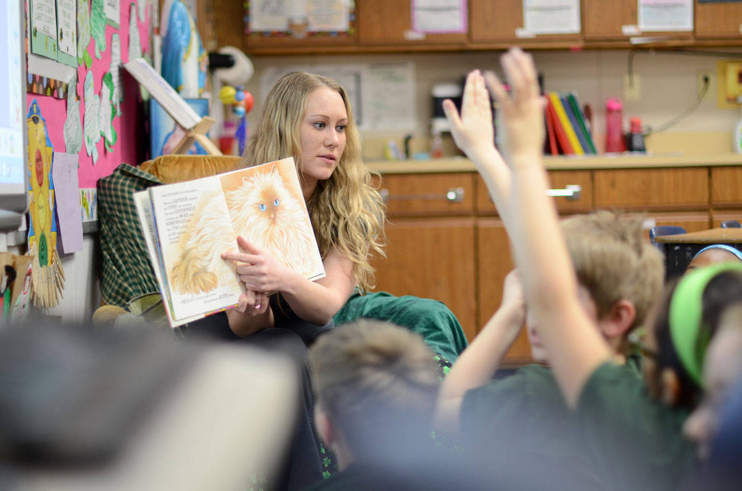Teacher reading a book to young students