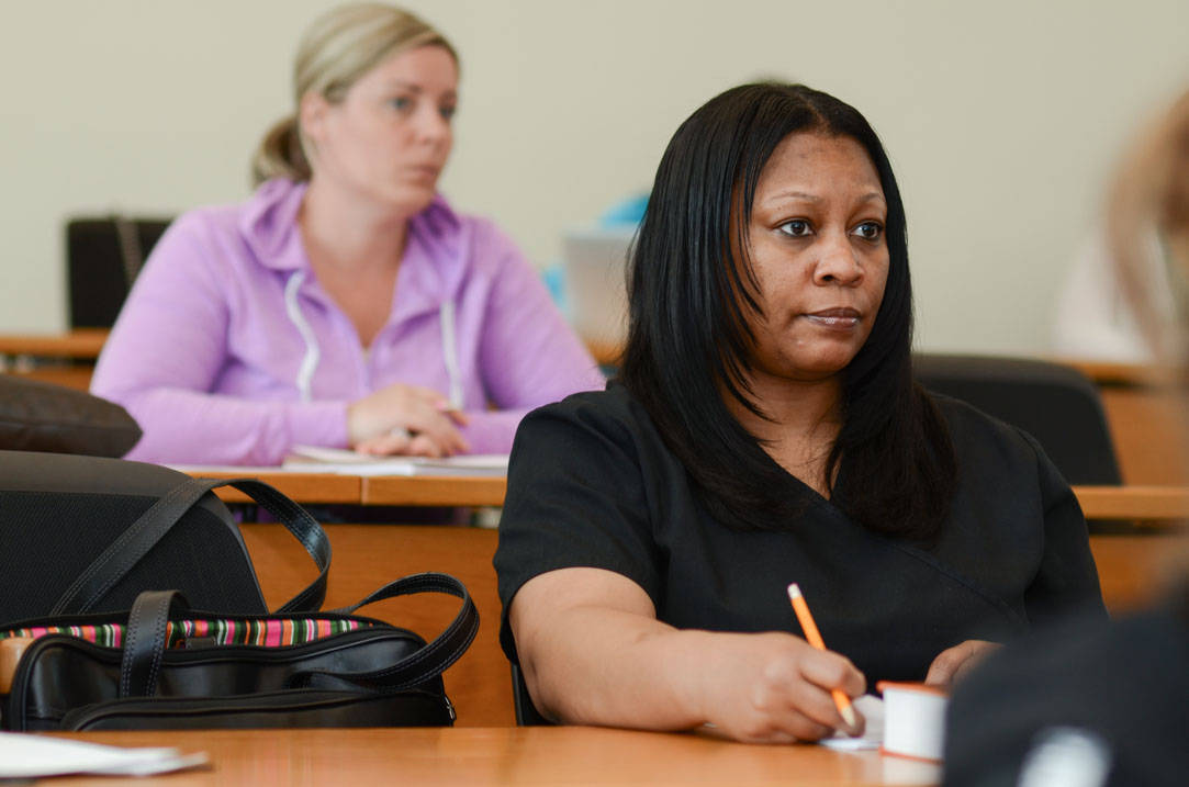 Two nursing students take notes during class