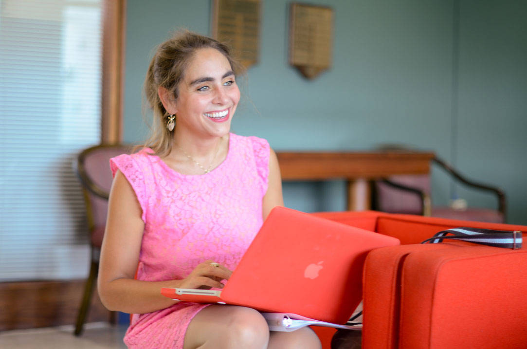 Humanities professor smile while working on laptop