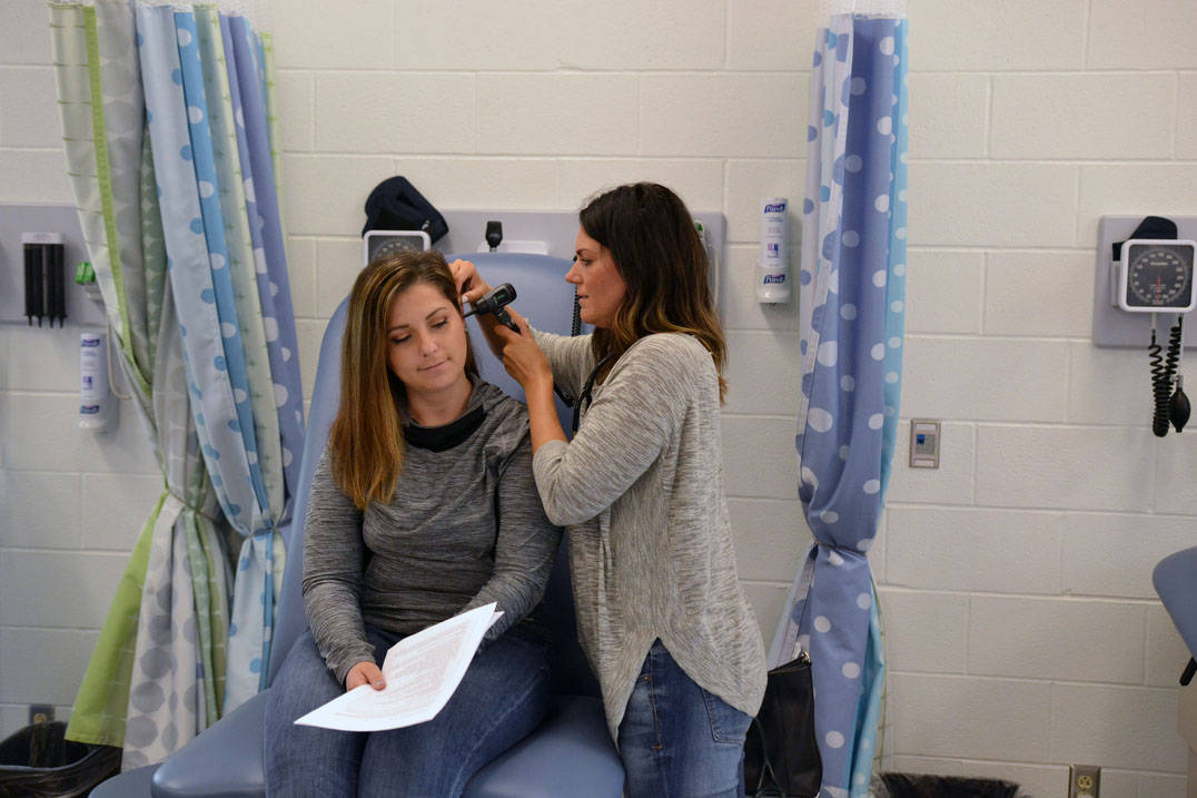 Student examines classmate's ear in nursing lab