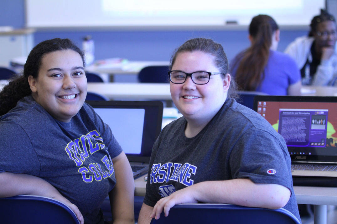 Two student smile together during class