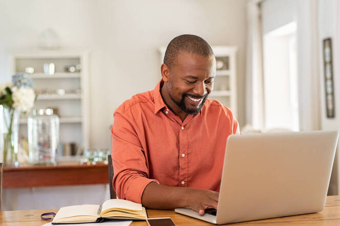 Male student doing course work at home on his laptop