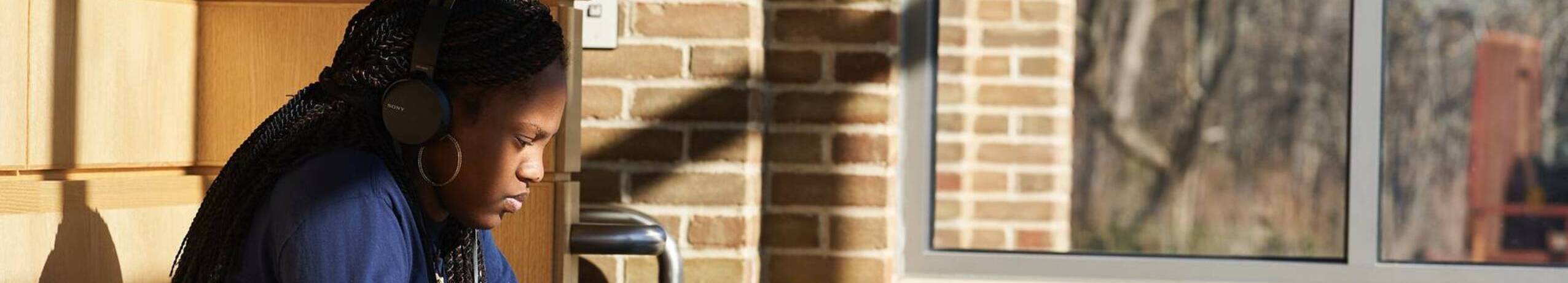 A student sits in a patch of sun on Ursuline College campus.
